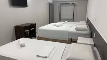 A hotel room with two beds, a desk, a chair, a TV, and an air conditioning unit.
