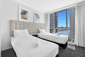 A hotel room with two beds, a large window with a view of a cityscape and water, and artwork on the wall. - 'Chevron Renaissance' - Level 8 - Riverside (Surfers Paradise)
