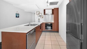 Een moderne keuken met een centraal eiland, roestvrijstalen apparatuur en een inbouwoven.