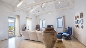 A spacious living area with a large white sofa, a rustic vase, and a view to the outside. - TROPEA VETERA Luxury Home - Oven House 1638 (Tropea)