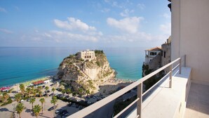 A coastal view with a building on a cliff, a beach with umbrellas, and parked cars. - TROPEA VETERA Luxury Home - Oven House 1638 (Tropea)