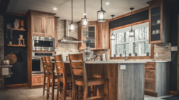 A kitchen with wooden cabinets, a central island with bar stools, stainless steel appliances, and pendant lighting.