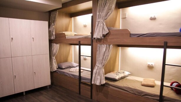 Une chambre de dortoir avec des lits superposés, une armoire et une petite fenêtre.
