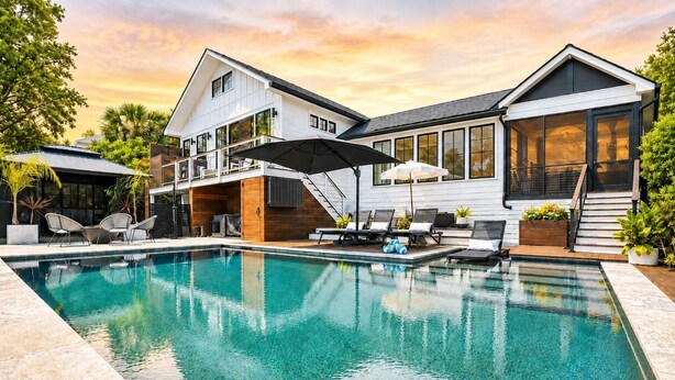 Ein modernes Haus mit Swimmingpool, Außenmöbeln und einer überdachten Terrasse.