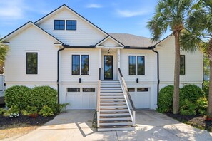 A two-story house with a front entrance, a staircase, and a garage. - Luxury Home with Waterway Views: Private Pool, Backyard Resort Oasis, 11 ppl (Isle of Palms)