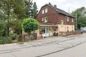 A two-story building with a porch, a wooden fence, and a bench. - Pension Kaufmann / Holiday Apartment for 1–3 Guests in Oberwiesenthal (Oberwiesenthal)