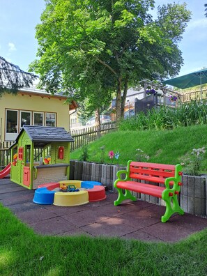 A children's play area with a slide, playhouse, and colorful play structures.