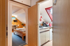A room with a bed, a desk, and a kitchenette.