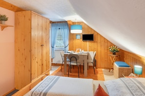 Une chambre mansardée chaleureuse, avec un lit, une petite table et une chaise.