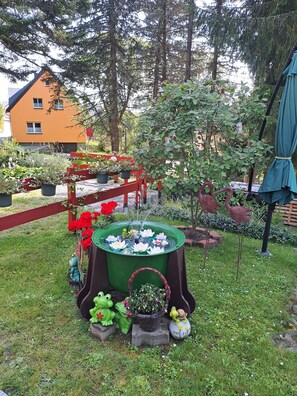 A garden with a pond, decorative frogs, and a red fence.