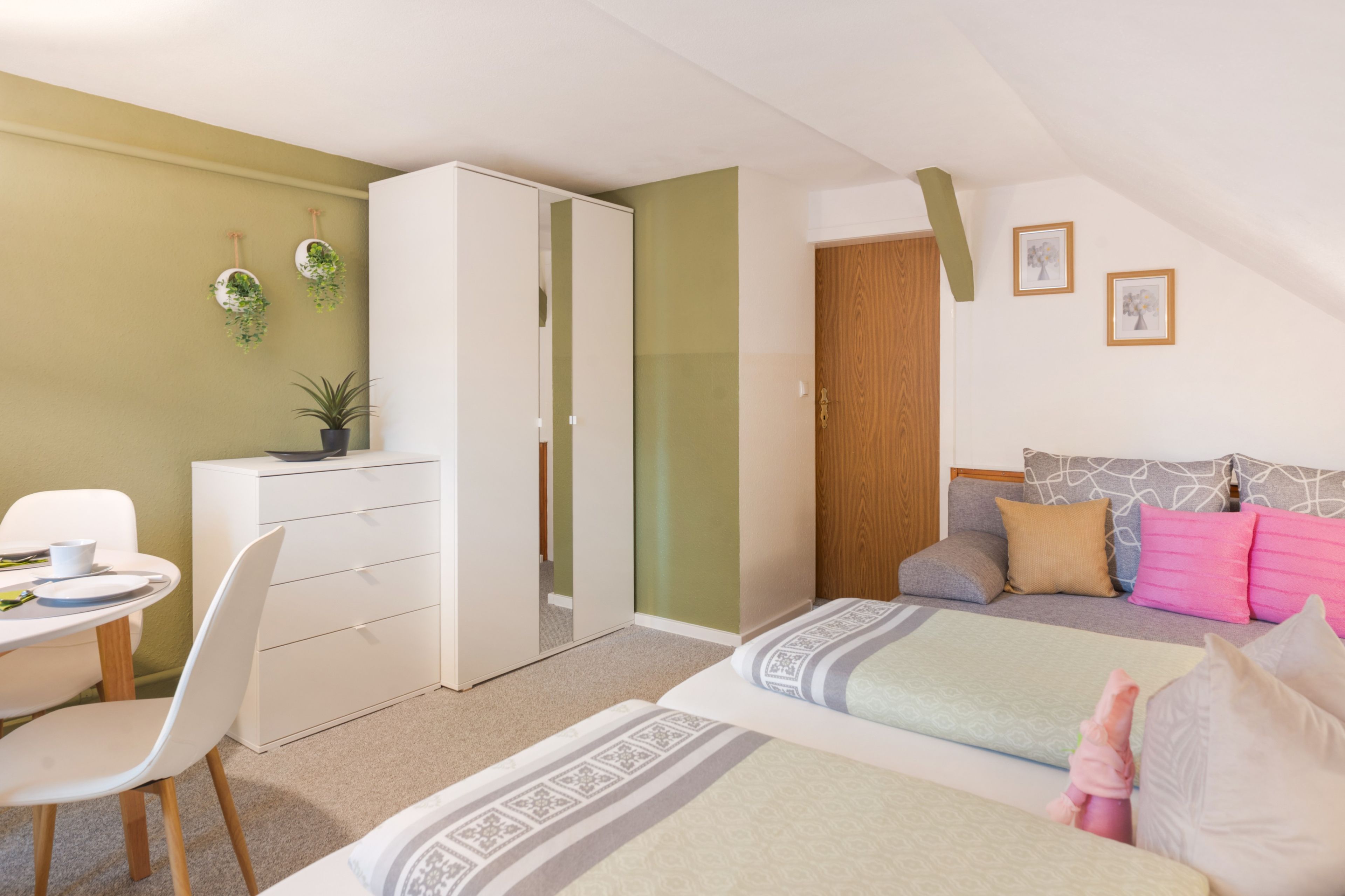 A bedroom with a bed, a desk, a chair, a wardrobe, and a door.