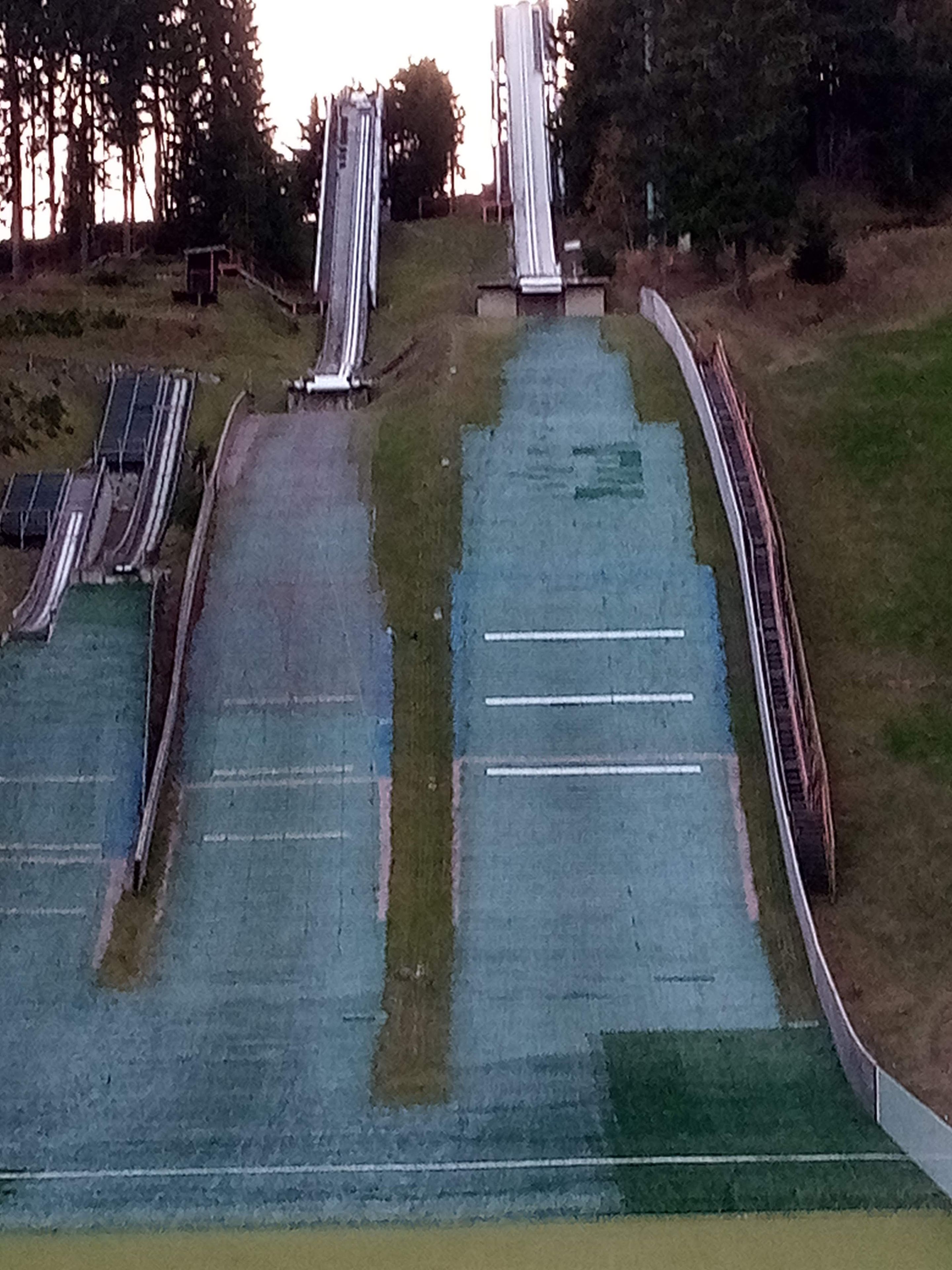 Eine Skipiste mit mehreren Abfahrten und einem Zaun, der das Gelände umgrenzt.
