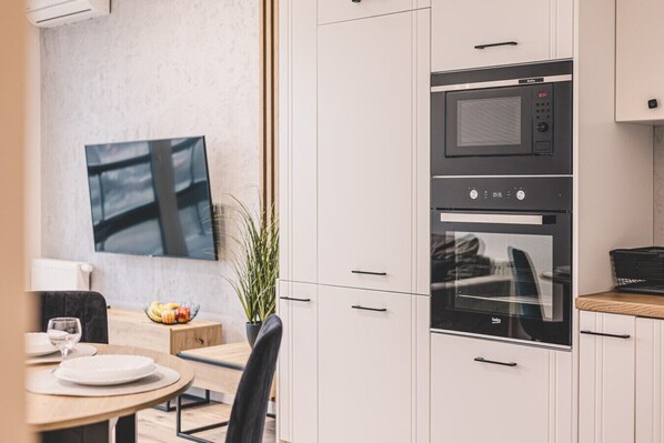 A modern kitchen with white cabinetry, a built-in oven, and a microwave.