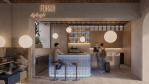 A bar area with a reception desk, stools, and a display of bottles.