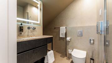Ein modernes Badezimmer mit großem Spiegel, Toilette, Dusche und Handtuchhalter.