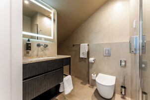 Un baño moderno con un espejo grande, un inodoro, una ducha y un perchero para toallas.