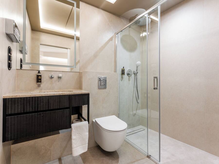 A modern bathroom with a glass-enclosed shower, a white toilet, and a dark-toned vanity.