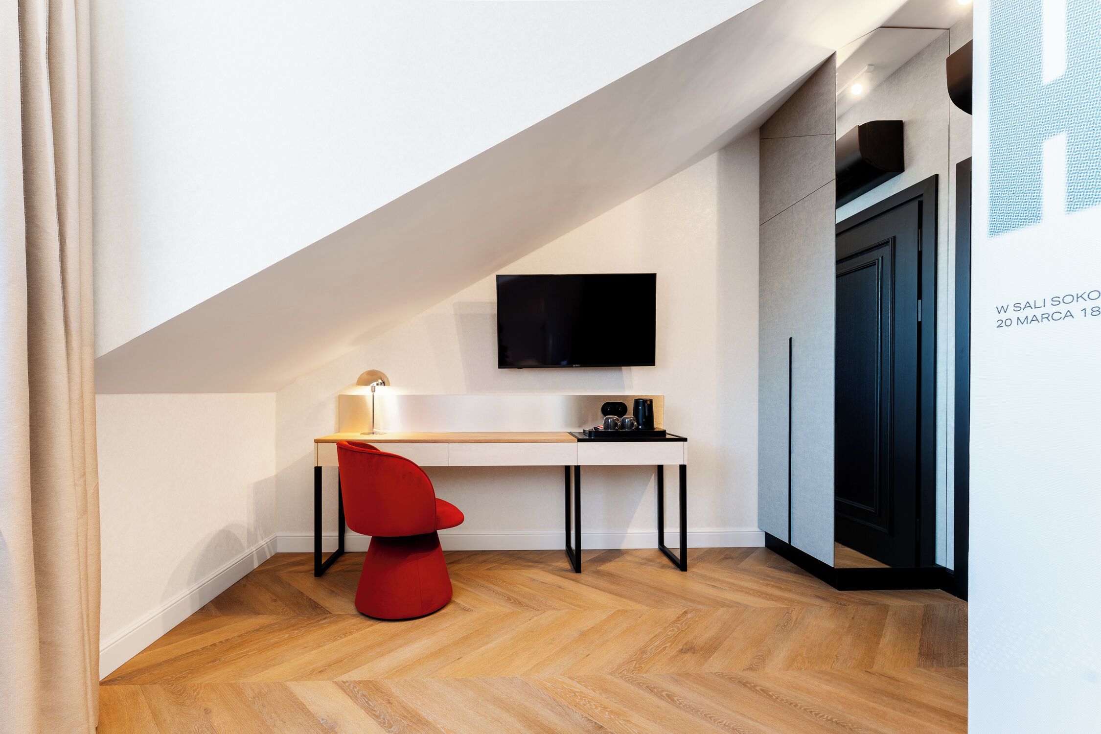 A modern room with a desk, chair, and a flat-screen TV mounted on the wall.
