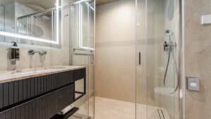 A modern bathroom with a glass-enclosed shower, a large mirror, and a dark wood vanity.