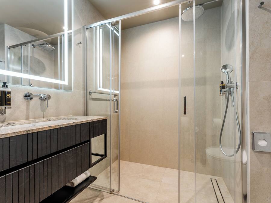 Une salle de bain moderne avec une douche à parois de verre, un grand miroir et un meuble-lavabo en bois foncé.