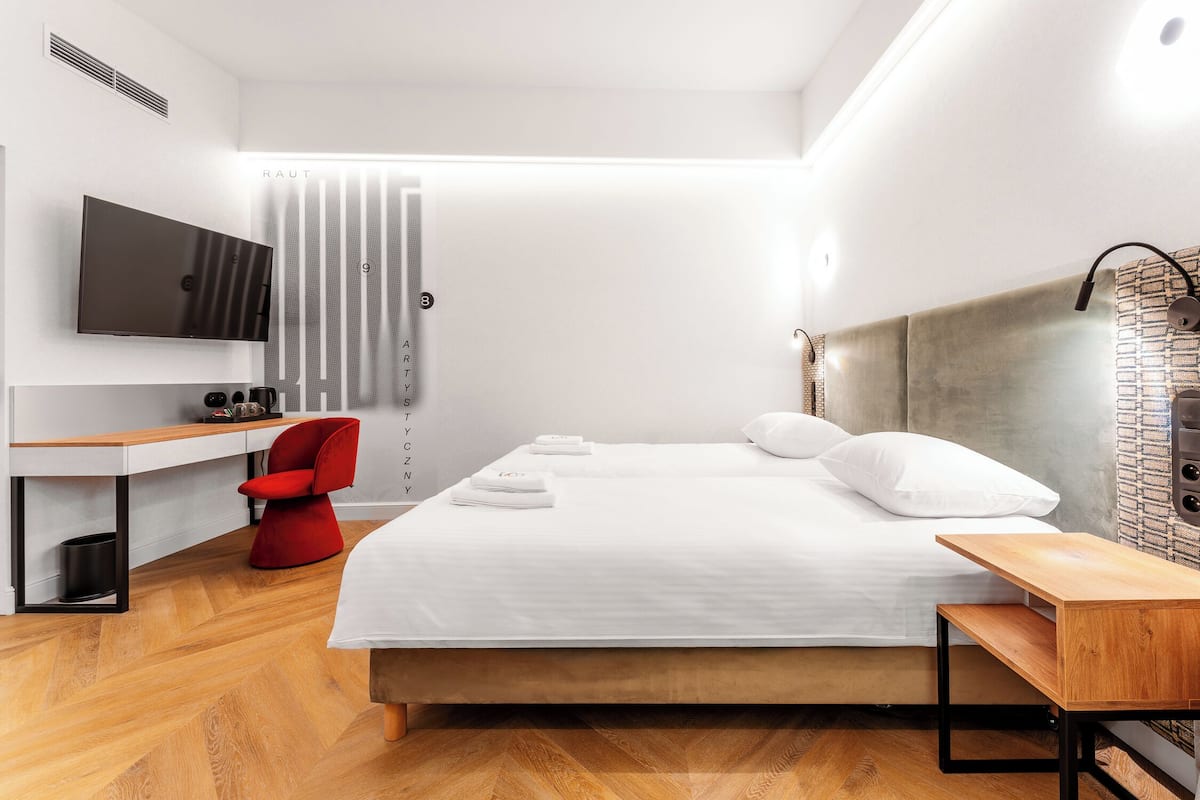 Een moderne hotelkamer met een bed, een bureau, een rode stoel, een televisie en een douche.