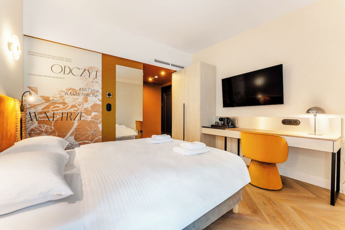Een hotelkamer met een bed, een bureau, een televisie en een muur met tekst.