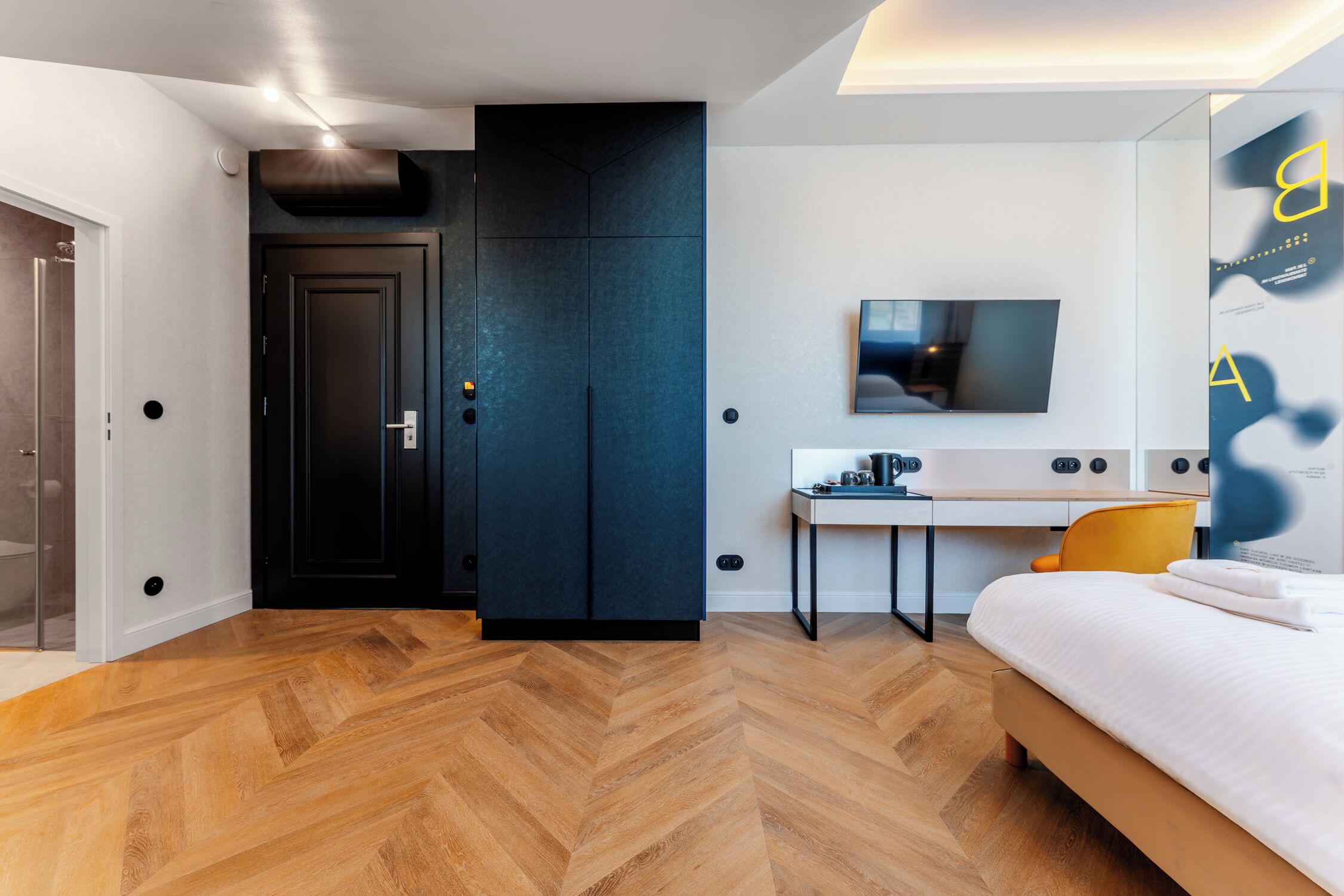 A modern bedroom with a bed, a desk, and a TV.