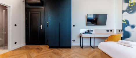 A modern bedroom with a bed, a desk, and a TV.