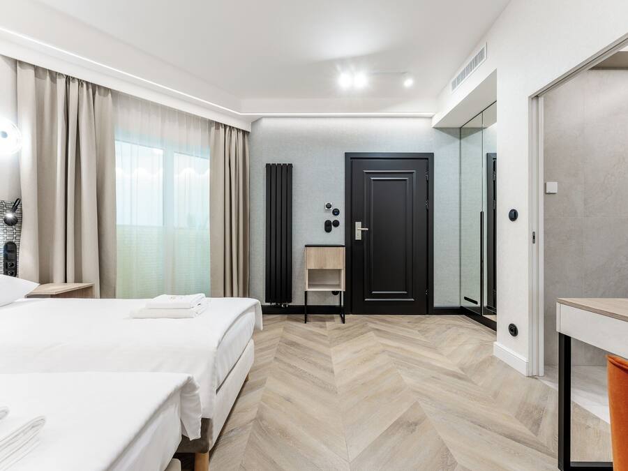 A hotel room with a bed, a desk, a wardrobe, and a bathroom.