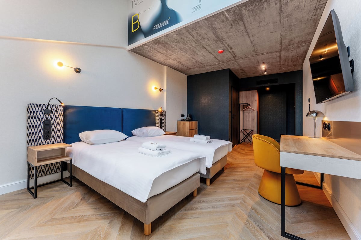 Een moderne hotelkamer met een bed, nachtkastjes, een bureau en een stoel.