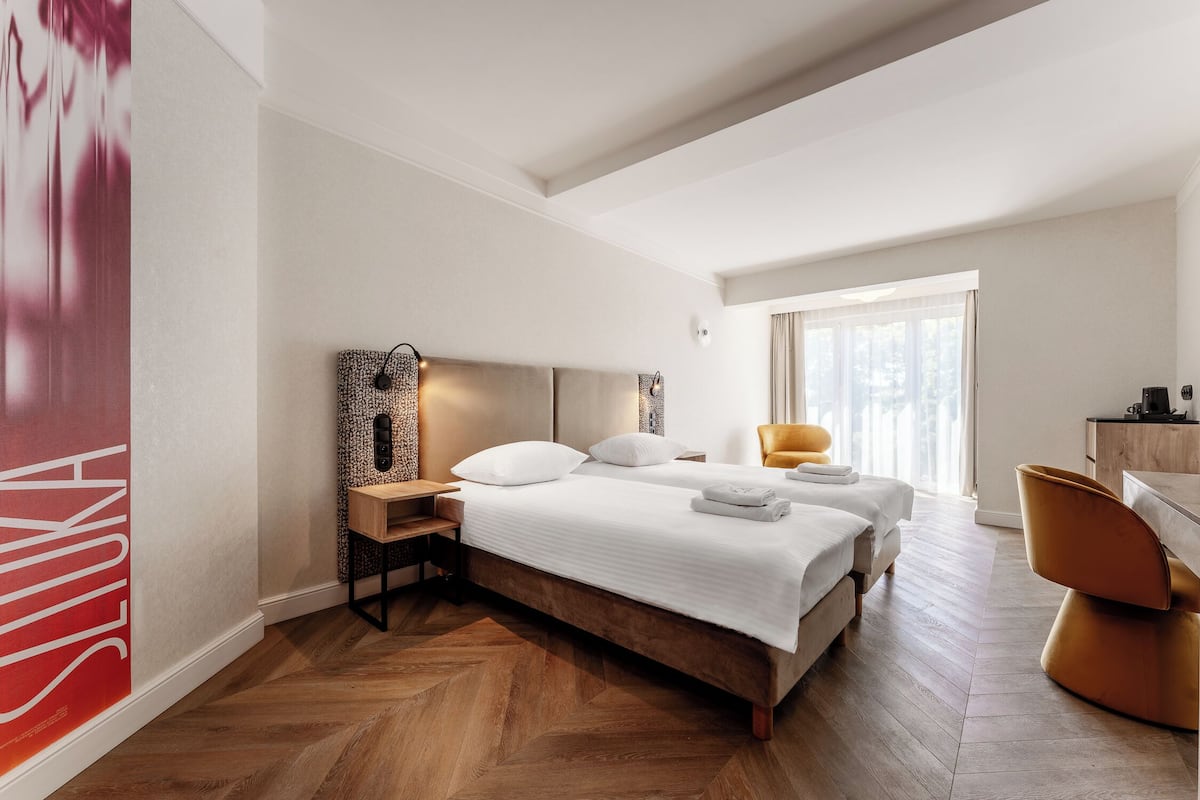 Een hotelkamer met een groot bed, een bureau, een stoel en een raam met gordijnen.