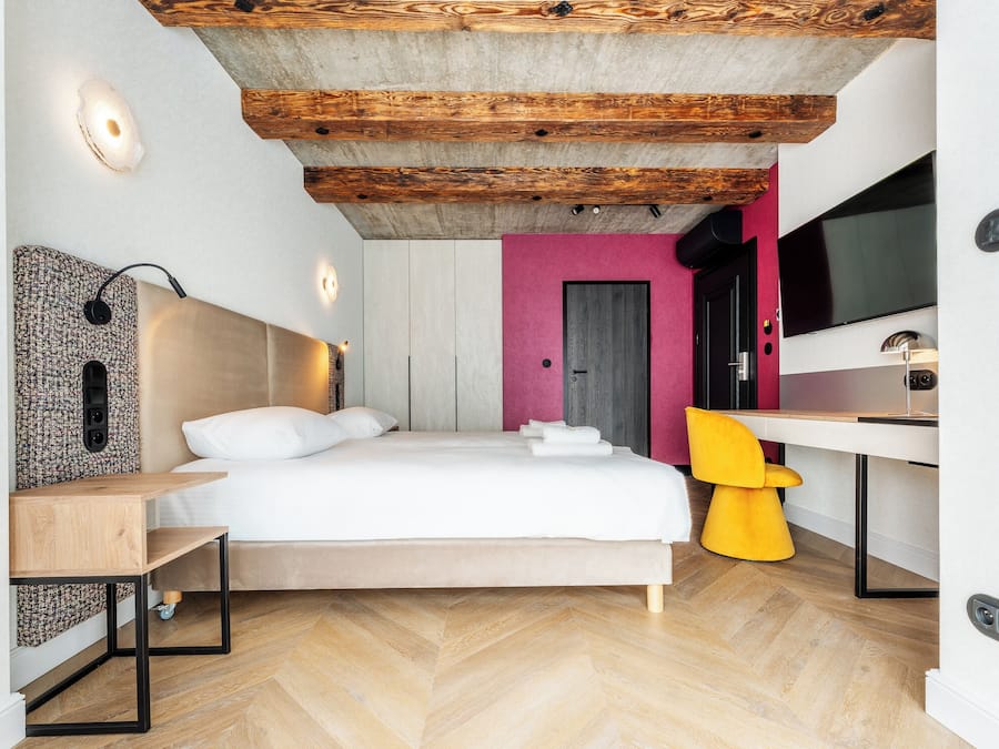 A modern bedroom with a bed, bedside table, and a desk with a chair.
