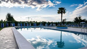 A swimming pool with lounge chairs and palm trees. - Villa Sara Resort (Venezia)