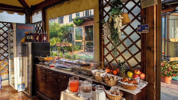 A breakfast buffet with various food items, a beverage station, and a view of the outdoor area. - Villa Sara Resort (Venezia)