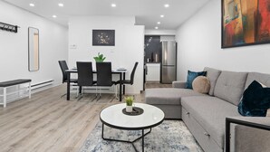 Una sala moderna con comedor, un sofá y una cocina al fondo.