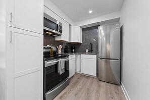 Une cuisine moderne avec des armoires blanches, des appareils en acier inoxydable et un comptoir en granit.