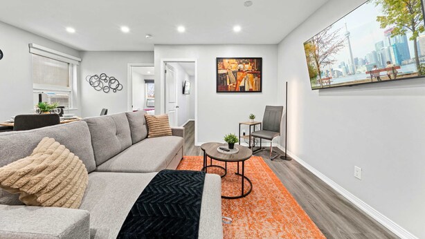 A modern living room with a sofa, coffee table, and artwork on the walls. - Modern Suite Near Dufferin Grove Transit Line (Toronto)