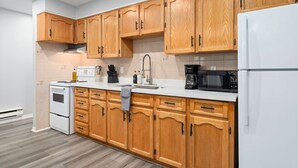 A kitchen with wooden cabinets, a white refrigerator, and a stove. - Modern Suite Near Dufferin Grove Transit Line (Toronto)