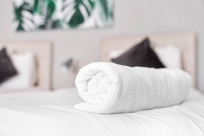 A neatly rolled white towel on a bed with a headboard and pillows. - Grand 5 Bedrooms and 3 Bath Birmingham Home (Birmingham)