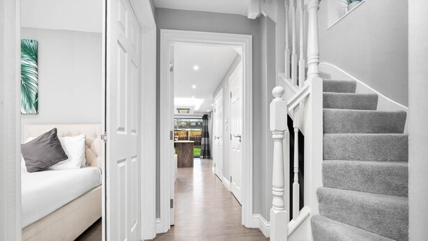 A hallway with a staircase, a bed, and a door leading to another room. - Grand 5 Bedrooms and 3 Bath Birmingham Home (Birmingham)