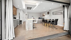A modern kitchen with a marble island, dining area with black chairs, and a large mirror on the wall. - Grand 5 Bedrooms and 3 Bath Birmingham Home (Birmingham)