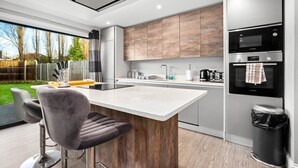 A modern kitchen with a central island, stainless steel appliances, and a view of the outdoors. - Grand 5 Bedrooms and 3 Bath Birmingham Home (Birmingham)