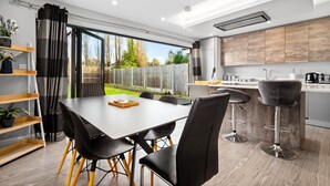 A modern kitchen with wooden cabinets, a dining area with a table and chairs, and a view of the backyard. - Grand 5 Bedrooms and 3 Bath Birmingham Home (Birmingham)