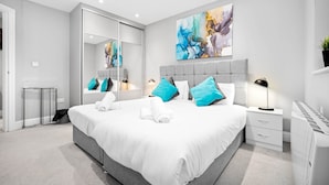 A modern hotel room with a large bed, a bedside table, a nightstand, a mirror, and a large abstract painting on the wall. - Grand 5 Bedrooms and 3 Bath Birmingham Home (Birmingham)