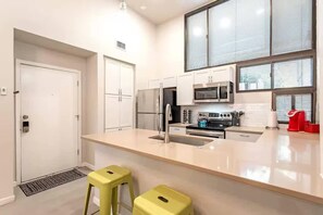 A modern kitchen with white cabinets, stainless steel appliances, and a large window. - Cozy Comfort and of Course a Pool +Spa (Tucson)