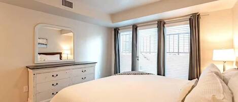 Un dormitorio con cama, cómoda, espejo y ventana con cortinas.
