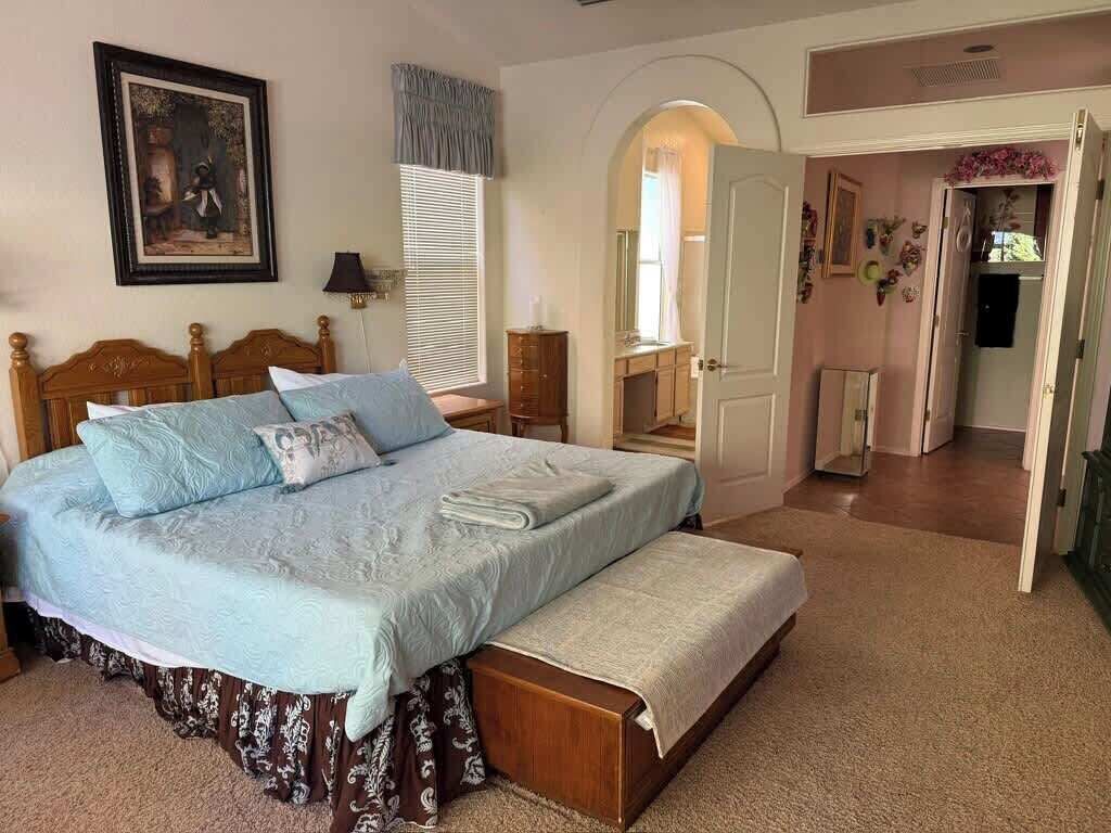 A bedroom with a large bed, a bedside table, a wardrobe, and an arched doorway leading to another room.