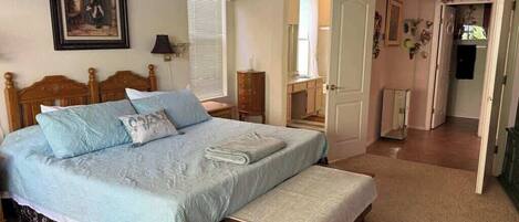 A bedroom with a large bed, a bedside table, a wardrobe, and an arched doorway leading to another room.