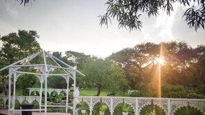 A gazebo with a white lattice roof, a pond with plants, and a fence with hanging planters. - Free Standing House in the Middle of Nature (Mbombela)