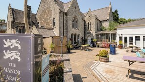 Een historisch stenen gebouw met een bord waarop 'The Manor Arms' staat.